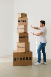 Man near carton boxes with many different words about stress.