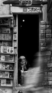 Woman reading behind a stack of books in a bookstore.