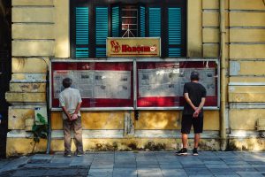 Two men reading the news at a Vietnam Newsstand.