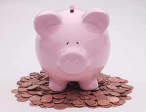 a pink ceramic piggy bank on a pile of coins
