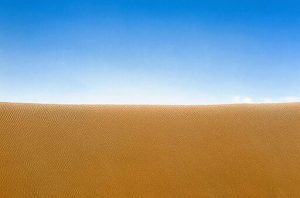 A sand dune meets the sky at the horizon.